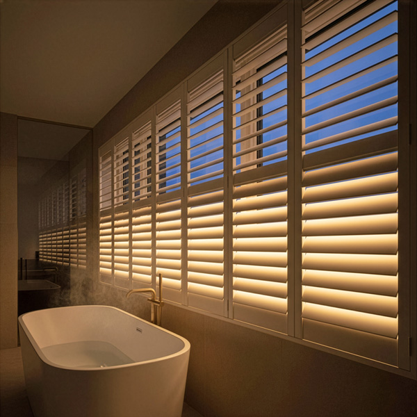A spa-like bathroom with LiteLüvr shutters glowing at dusk
